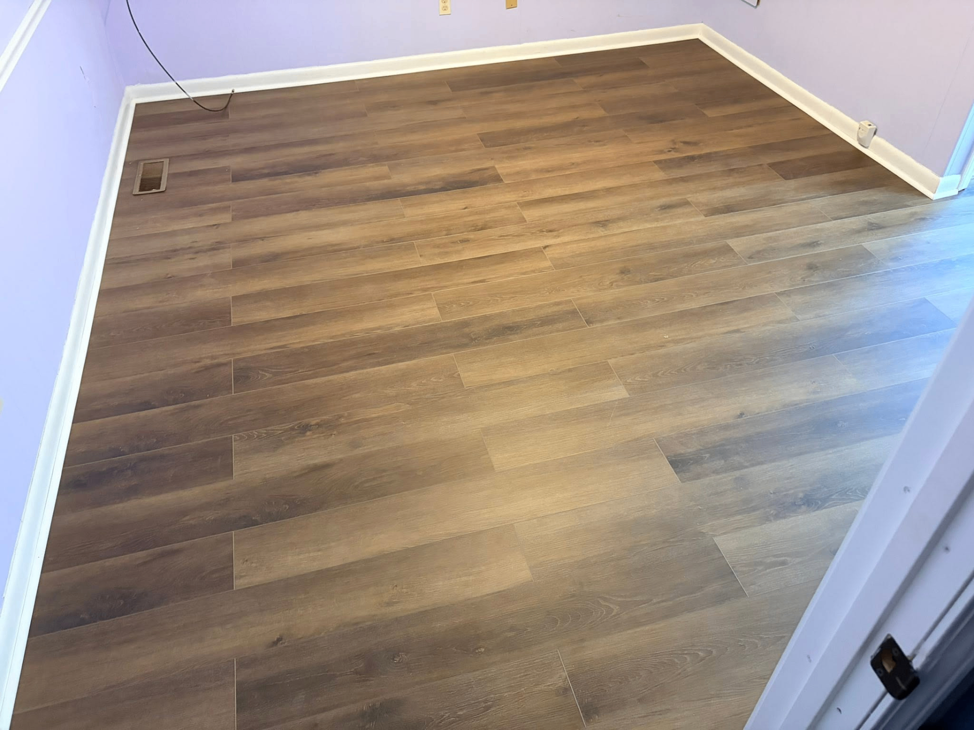 Freshly installed wide-plank vinyl wood flooring in a bedroom