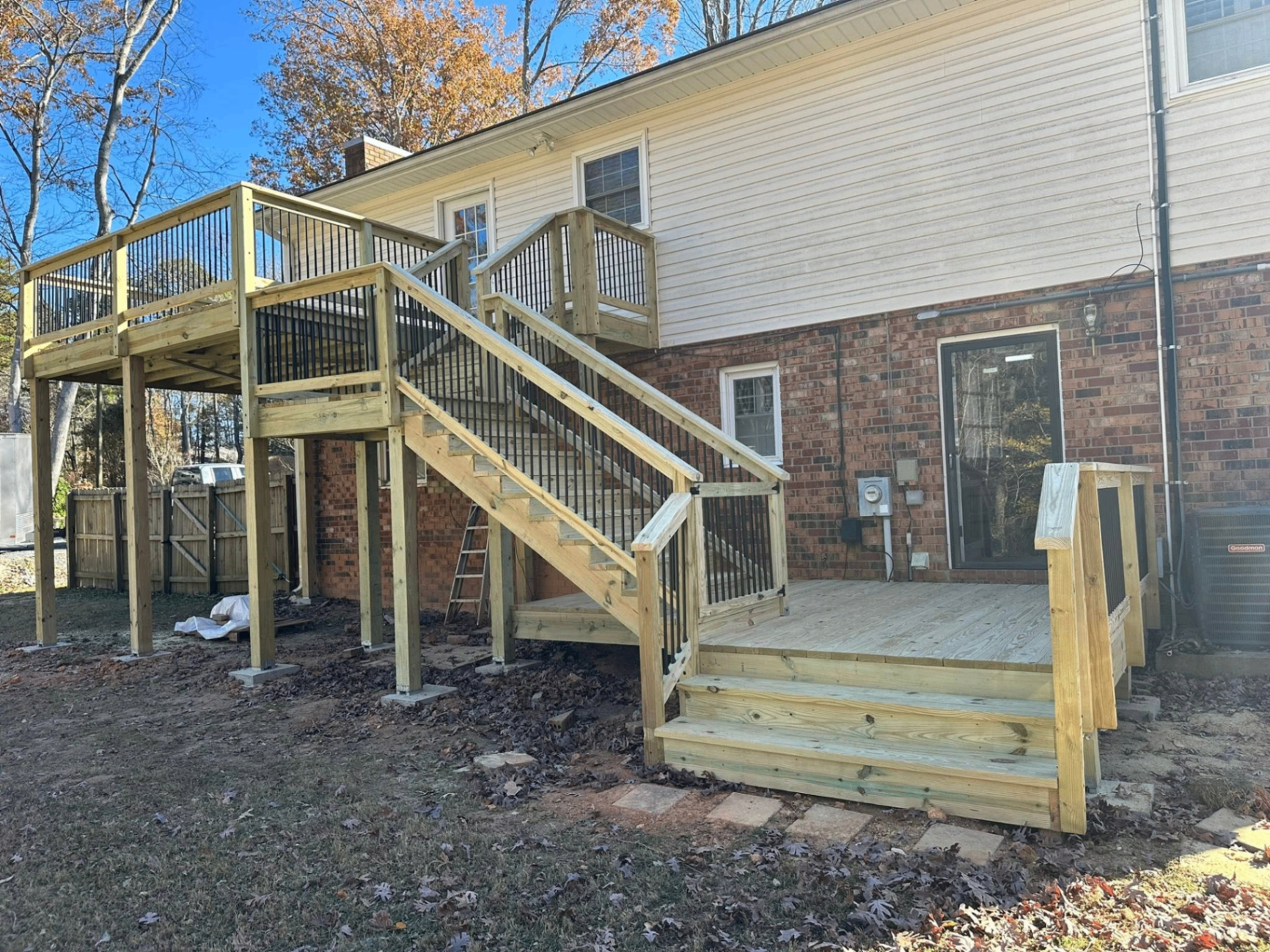 Two-story pressure-treated deck with full staircase against a brick home